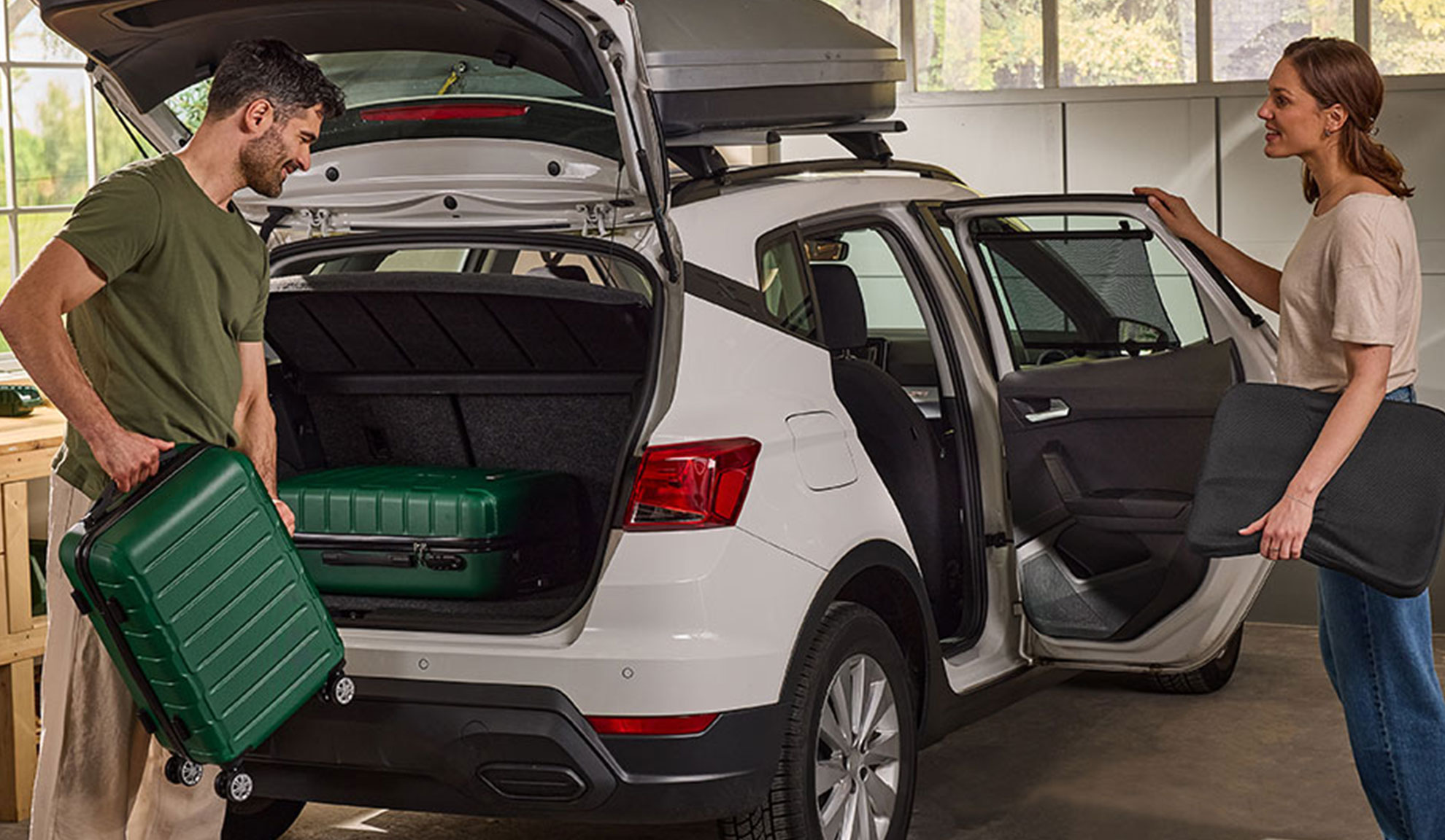 Paar packt Gepäck und Autozubehör in einen weißen SUV für eine Reise.
