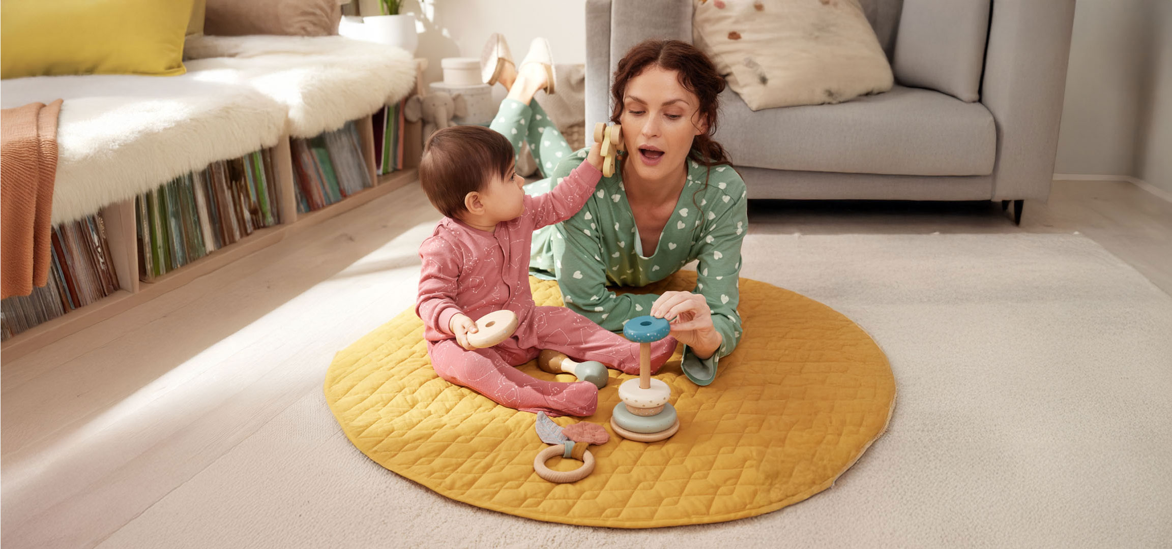 Mutter und Baby spielen mit Spielzeug auf dem Boden.