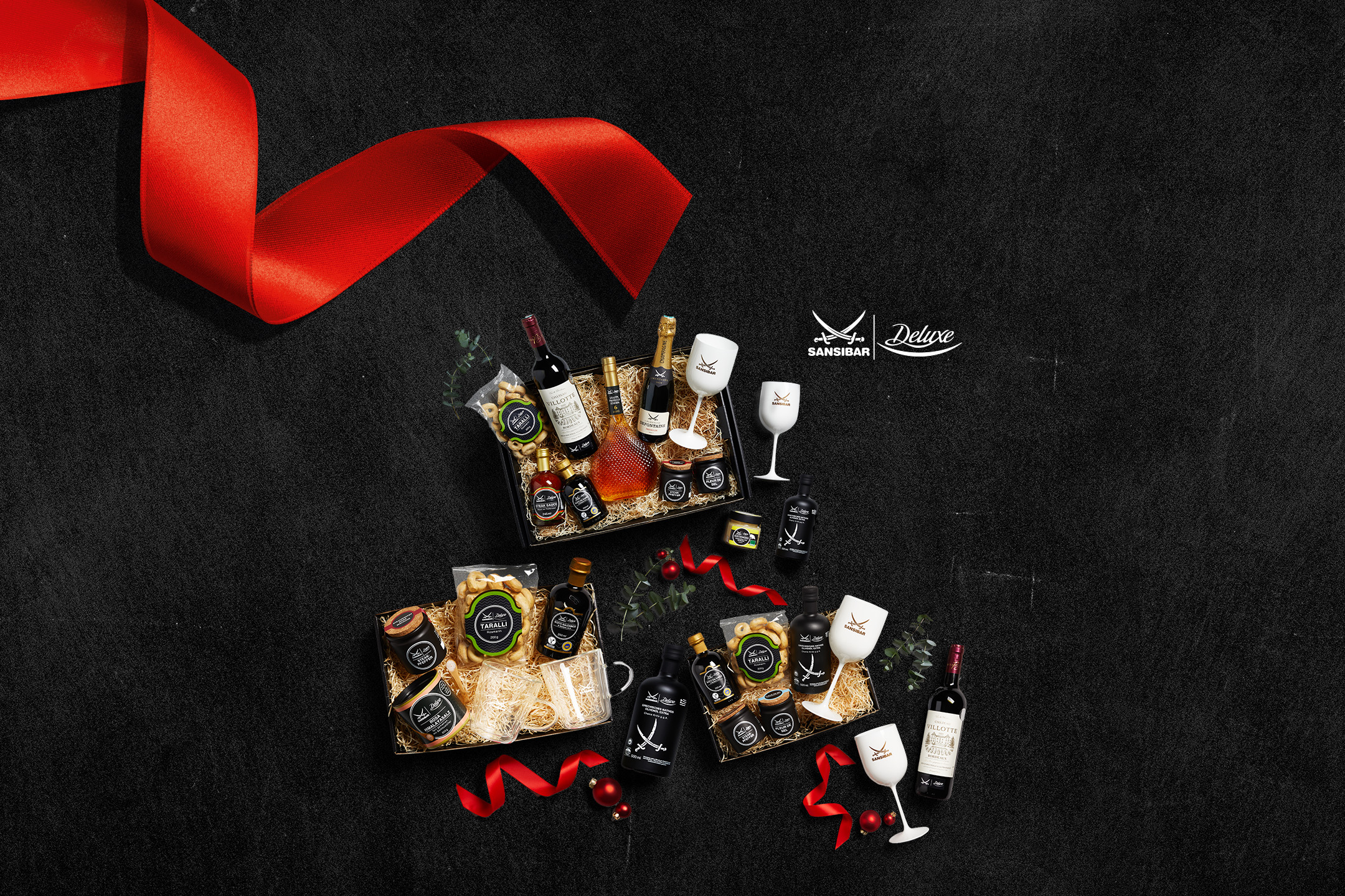 Sansibar Deluxe Geschenkkörbe mit Wein, Champagner, Olivenöl, Taralli und Weingläsern.