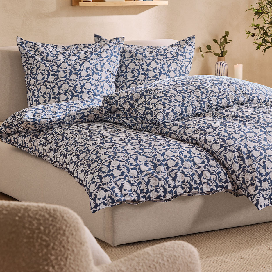 Bett mit blauer und weißer Blumenbettwäsche, Kissen und Decke