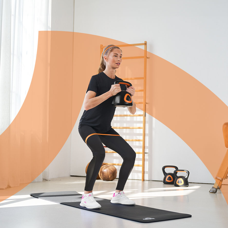 Frau macht Kniebeugen mit Kettlebell und Widerstandsband auf einer Fitnessmatte.