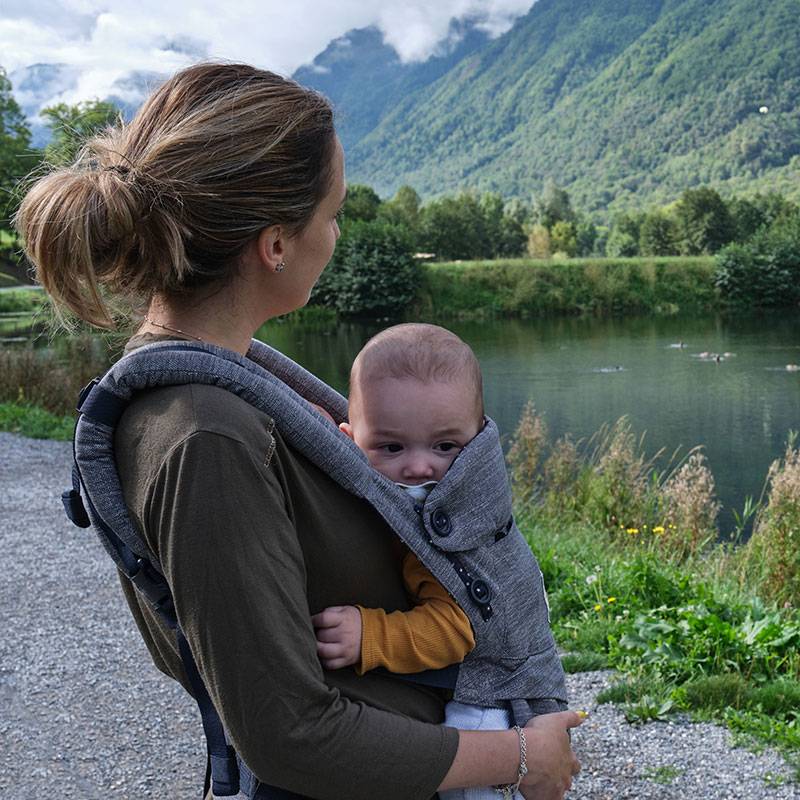Mutter mit Baby in Tragehilfe im Freien.