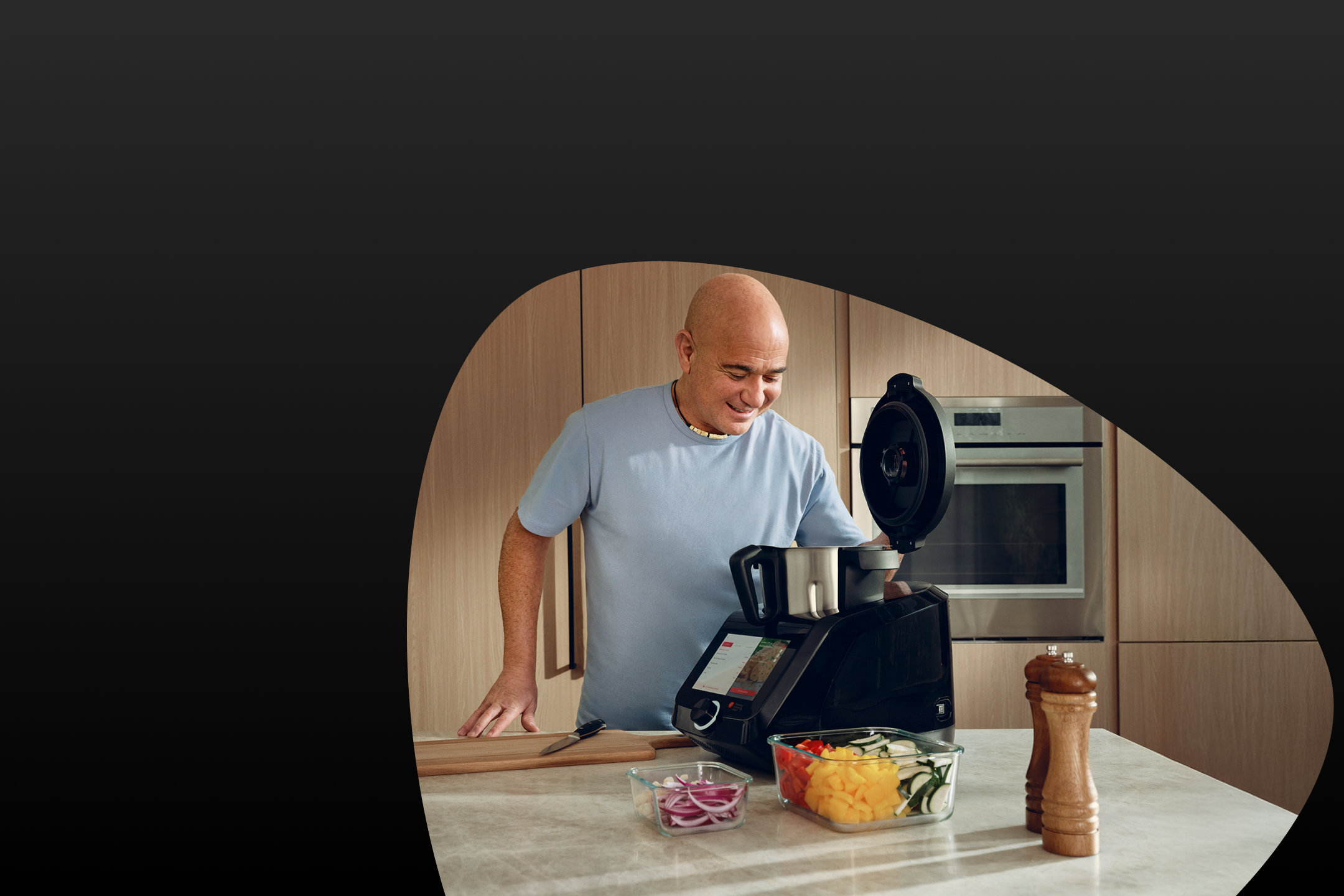 Mann kocht in der Küche mit einer Küchenmaschine und geschnittenem Gemüse.