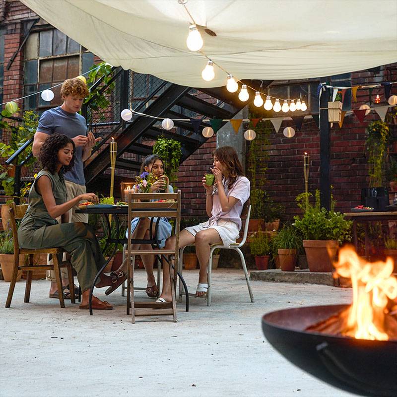 Freunde genießen ein Abendessen im Freien unter Lichterketten.