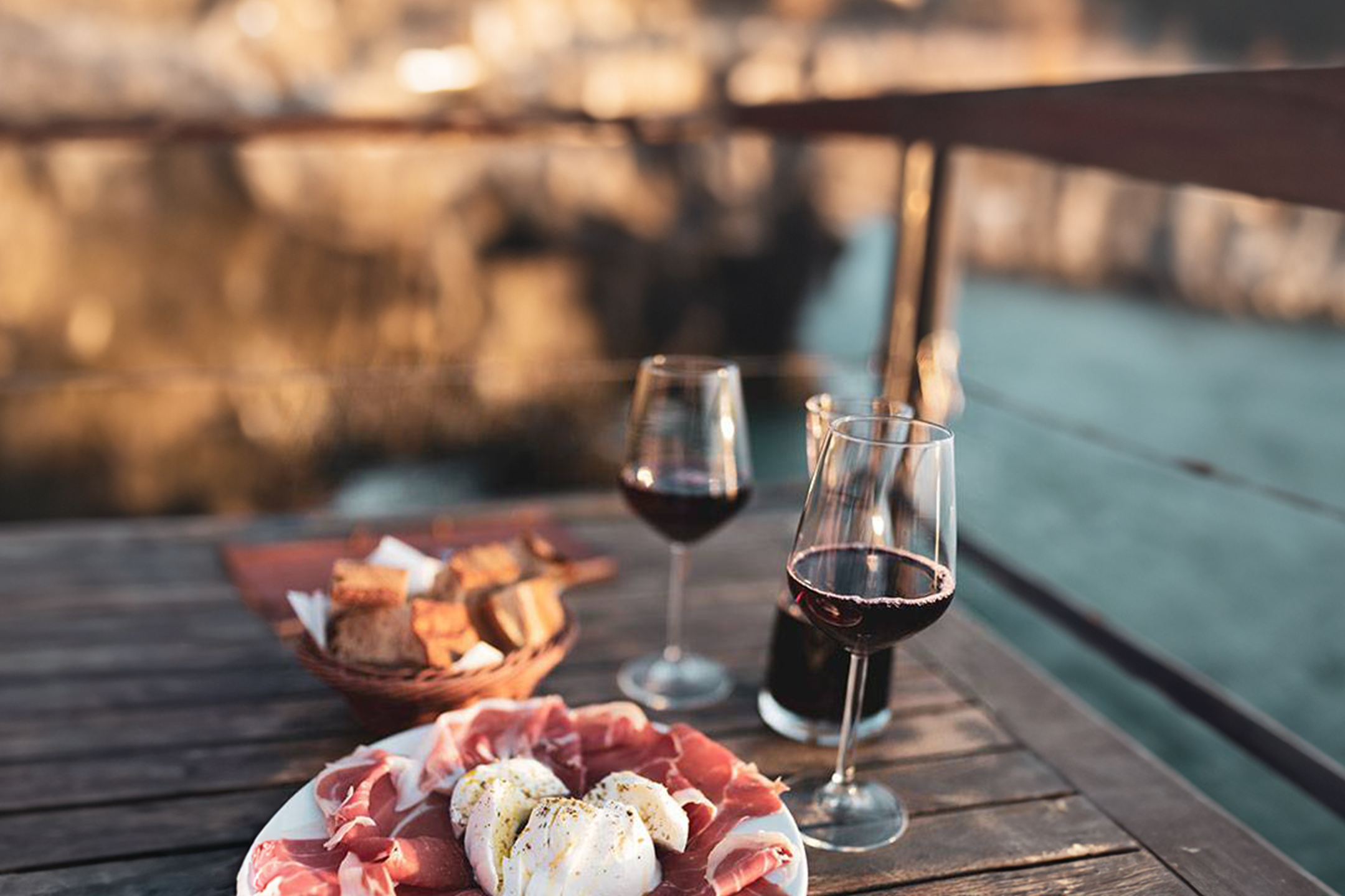 Wein, Prosciutto und Mozzarella auf einem Tisch im Freien.