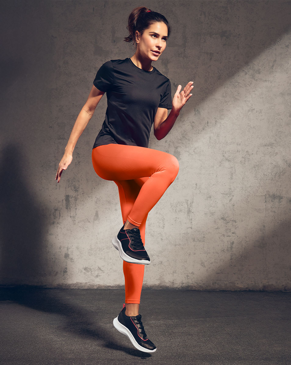 Frau in schwarzem Sport-T-Shirt und orangefarbenen Leggings beim Training