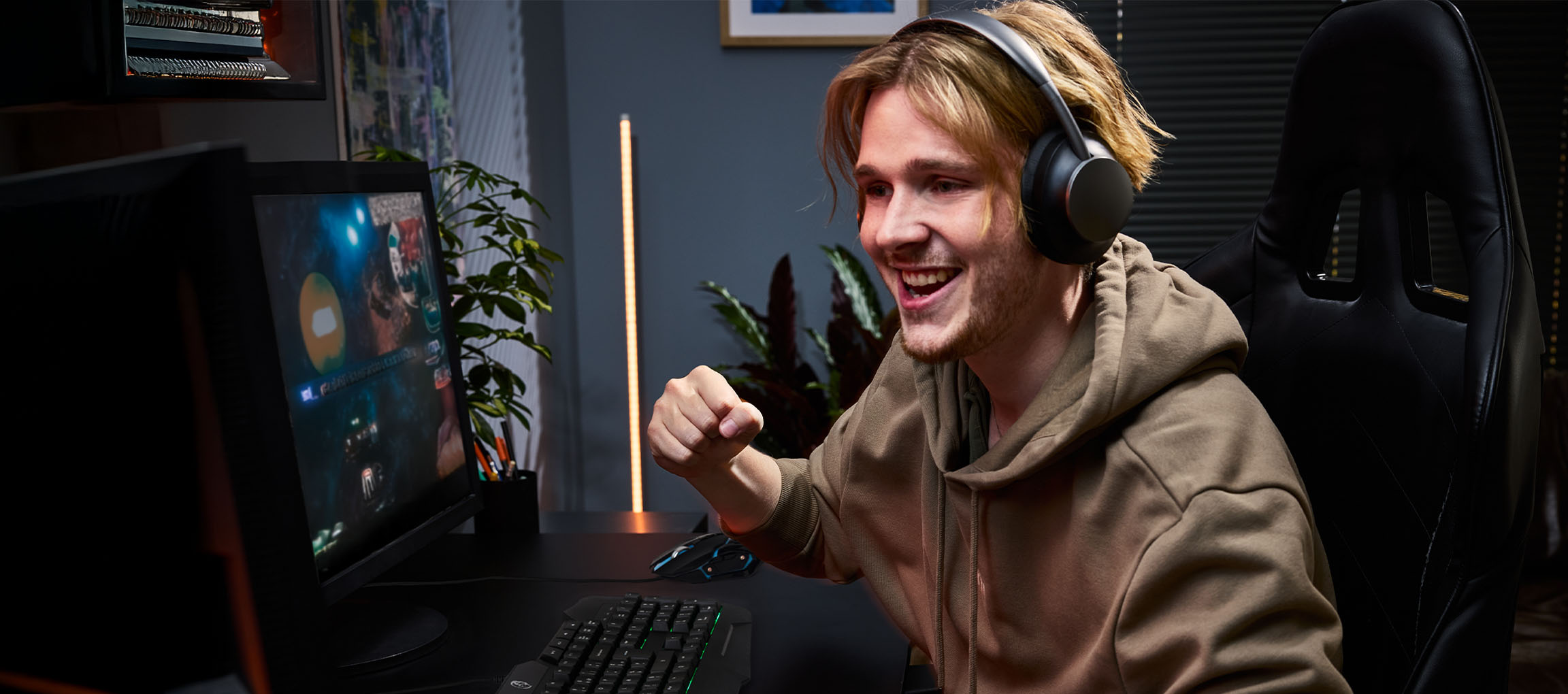 Junger Mann mit Kopfhörern spielt Videospiele mit Gaming-Tastatur und -Maus