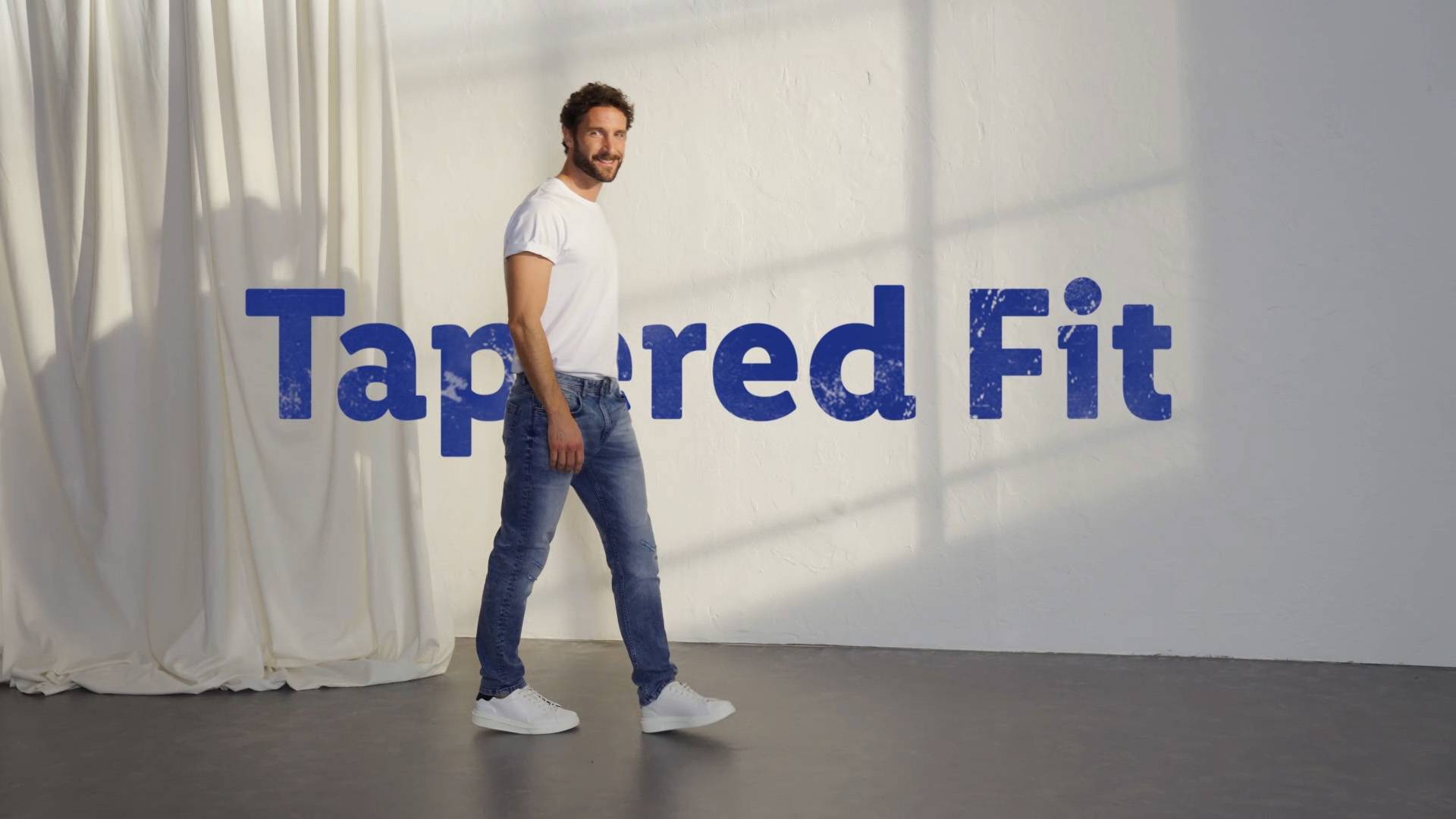 Mann trägt Jeans mit Tapered Fit.