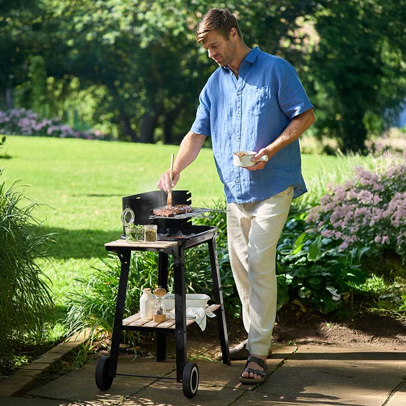 Mann grillt Steaks auf einem Holzkohlegrill.